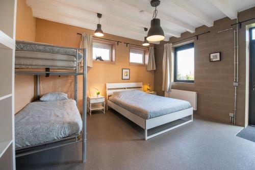 a bedroom with two bunk beds and two windows at DE SMISHOEVE met speelruimte, dieren en wellness in Heers