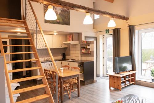 a kitchen and dining room with a wooden table and a staircase at DE SMISHOEVE met kinderpret, dieren en wellness in Heers