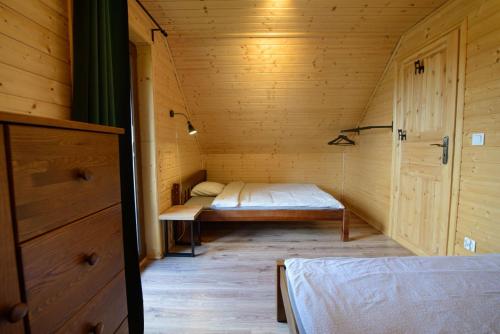 a small room with a bed in a wooden cabin at Całoroczny Domek Sosenka 1-5 z 2 sypialniami, aneksem, łazienka i salon in Milicz