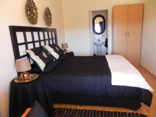 Schlafzimmer mit einem schwarzen und weißen Bett und einem Tisch in der Unterkunft J&B Lodge in Underberg