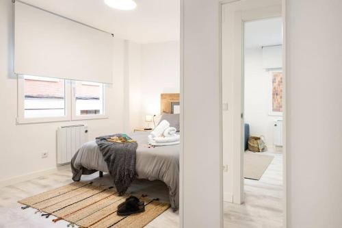 a white bedroom with a bed and a window at Piso en el corazón de Gijón in Gijón