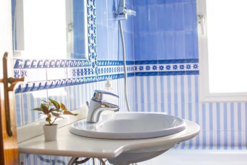 um lavatório branco numa casa de banho com azulejos azuis e brancos em MI RETIRO SEVILLANO em Sevilha