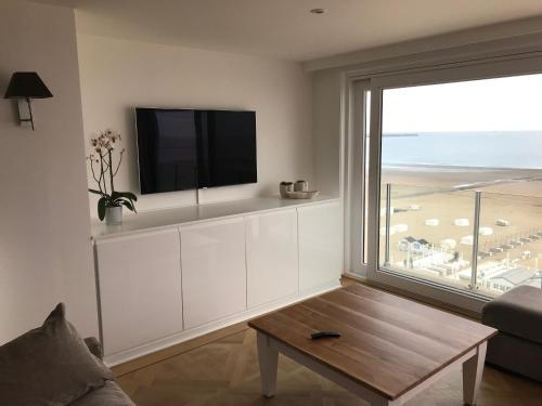 ein Wohnzimmer mit einem großen Fenster und einem TV in der Unterkunft Knokke Sea, Appartement Vue mer in Knokke-Heist