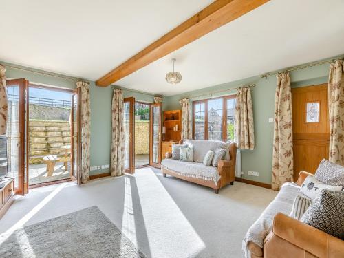 a living room with a couch and windows at The Farm House in Shipton under Wychwood