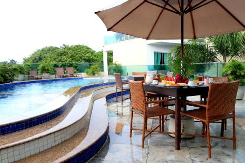 een tafel met stoelen en een parasol naast een zwembad bij Star Hotel in Jericoacoara