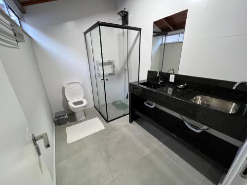 ein Badezimmer mit einem Waschbecken, einem WC und einem Spiegel in der Unterkunft Apartamento Frente Mar Vista Lateral in Bombinhas