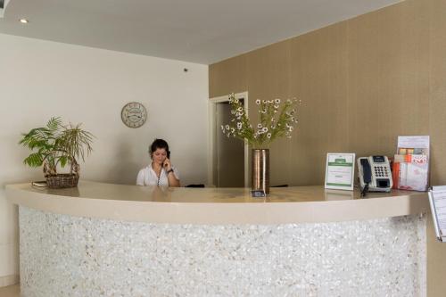 a woman talking on a cell phone behind a counter at Zante Plaza Hotel & Apartments in Laganas