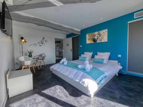 MoncautにあるGîte de la Tourmaline magnifique maison en pierreの青い壁のベッドルーム1室(大型ベッド1台付)