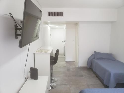 1 dormitorio con 1 cama, TV y escritorio en Av. Corrientes 818 - Ciudad de Buenos Aires - en Buenos Aires