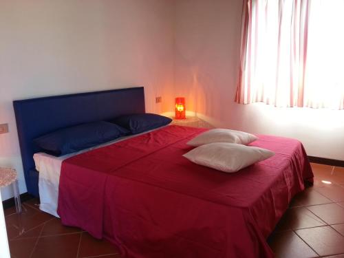 una camera con un letto rosso con due cuscini sopra di Villa Kandinskij A a Stintino