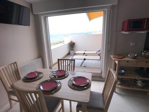 une salle à manger avec une table et des chaises et une grande fenêtre dans l'établissement Appartement T3 face à la mer avec terrasse panoramique et parking privé - Le Barcarès - FR-1-81-466, au Barcarès