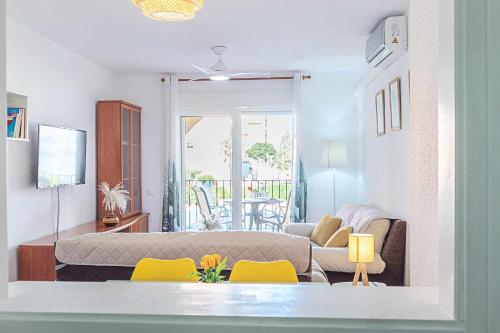 ein Wohnzimmer mit einem Sofa und gelben Stühlen in der Unterkunft Casa Playa Bonita Primera linea de playa in Roquetas de Mar