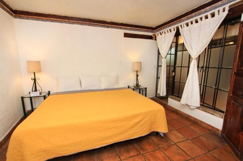 a bedroom with a yellow bed in a room with windows at Hotel Real Guanajuato in Guanajuato