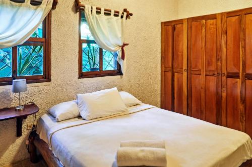 a bedroom with a large bed and two windows at Havana Lodge in Mal País