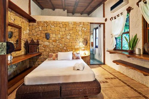 a bedroom with a bed and a stone wall at Havana Lodge in Mal País