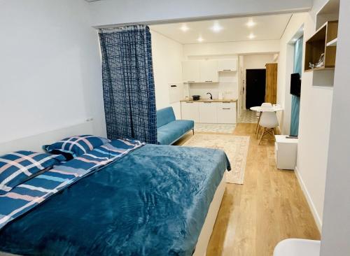 a bedroom with a blue bed and a kitchen at Bright n' Blue Studio with Mountain View in Almaty