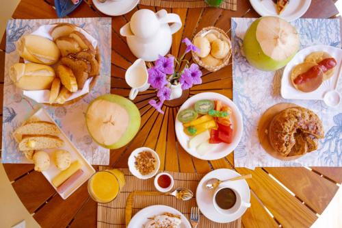 a wooden table topped with plates of food and fruit at Pousada Luar da Ilha in Fernando de Noronha