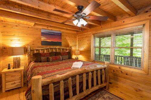 a log cabin bedroom with a bed and a ceiling fan at A Beary Good Time in Boone