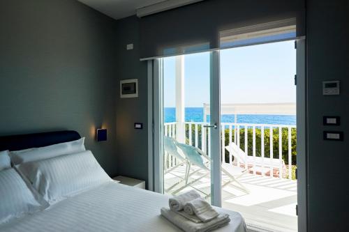 a bedroom with a bed and a balcony with the ocean at I Vereti in Patù