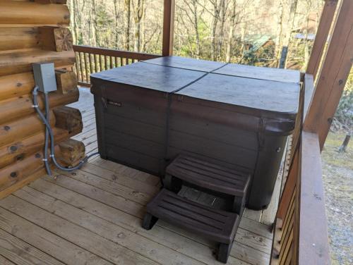 a wooden stove on a porch with a wooden stool at Almost There in Blowing Rock