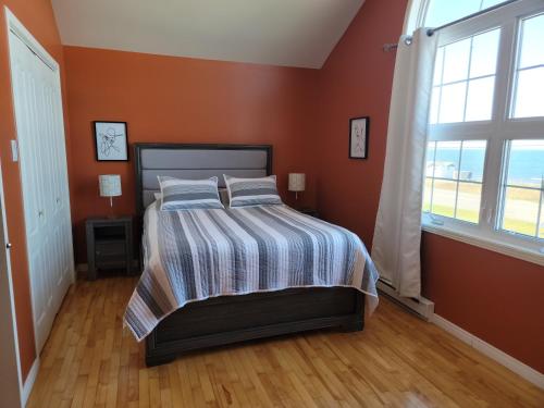 a bedroom with a bed with orange walls and a window at Motel de la mer in Rimouski