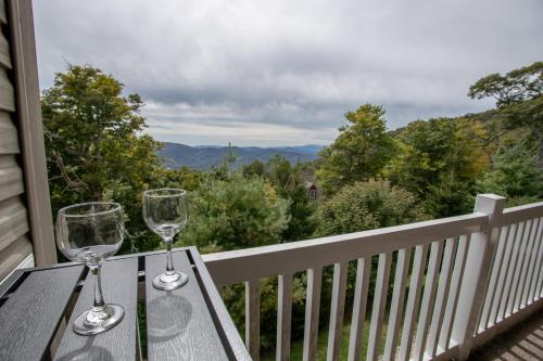 two wine glasses sitting on a wooden table on a balcony at Bear Necessities in Beech Mountain