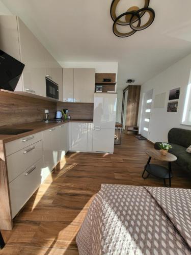 a kitchen with white cabinets and a living room at Studio apartman Pegi in Šimuni