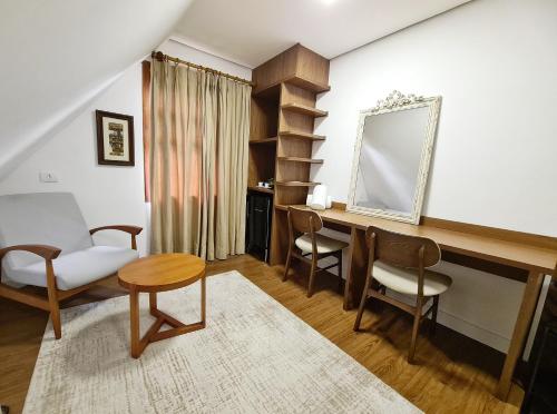 a living room with a table and chairs and a mirror at Casa Três Rios - Campos do Jordão in Campos do Jordão