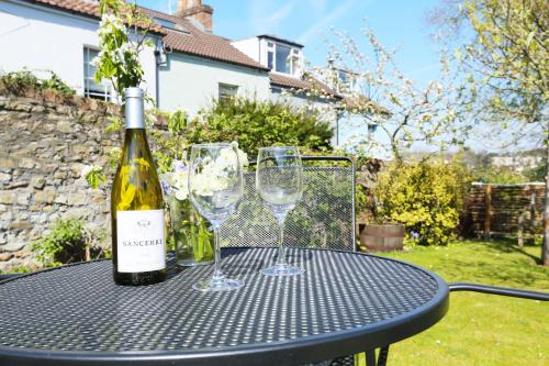 uma garrafa de vinho e dois copos de vinho numa mesa em Old Stables, hidden period gem, spectacular garden em Bristol