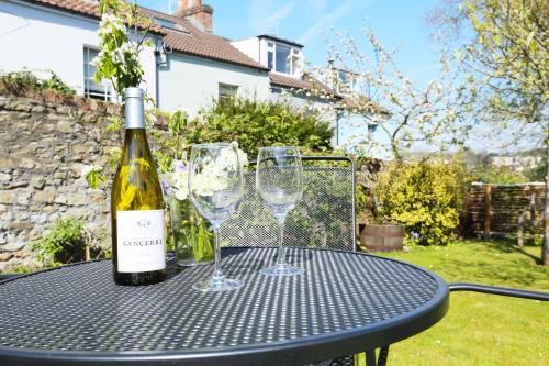 a bottle of wine and two wine glasses on a table at Old Stables, hidden period gem, spectacular garden in Bristol