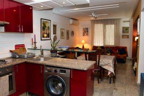 une cuisine avec des placards rouges et un salon dans l'établissement DESiGN UNQUE appartement, à Sousse