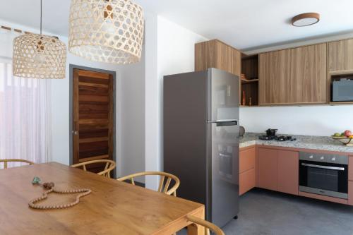 a kitchen with a wooden table and a stainless steel refrigerator at Barra Grande, Maraú, Casa 5 in Marau