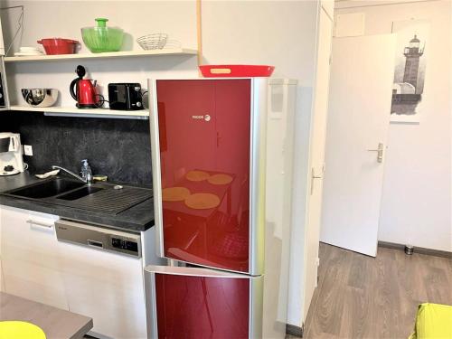 - un réfrigérateur rouge dans la cuisine avec évier dans l'établissement Appartement rénové, bien équipé à 500m de la plage de Trestrignel et du centre-ville de Perros-Guirec - FR-1-368-241, à Perros-Guirec