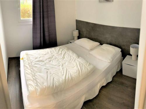 une chambre avec un lit blanc et une fenêtre dans l'établissement Appartement rénové, bien équipé à 500m de la plage de Trestrignel et du centre-ville de Perros-Guirec - FR-1-368-241, à Perros-Guirec
