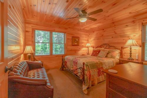 a log cabin bedroom with a bed and a ceiling fan at Breathe Easy in Vilas