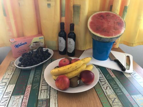 a table with a plate of fruit and two bottles of wine at Babsi Appartments - leben am Land in Wels
