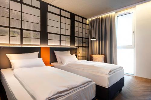 a hotel room with two beds and a window at LOGINN Hotel Waiblingen in Waiblingen