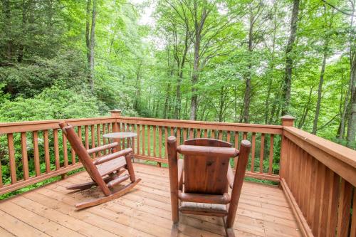 a wooden deck with two chairs and a table on it at Creek Sound Chalet in Blowing Rock