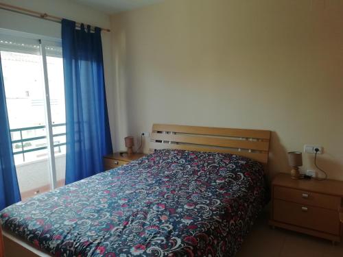 ラ・ヌシアにあるApartamento Betaniaのベッドルーム1室(ベッド1台、青いカーテン付きの窓付)