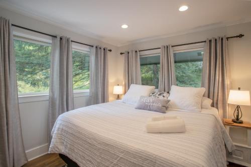 a bedroom with a large white bed with windows at Eagles Nest on Seven Devils in Seven Devils