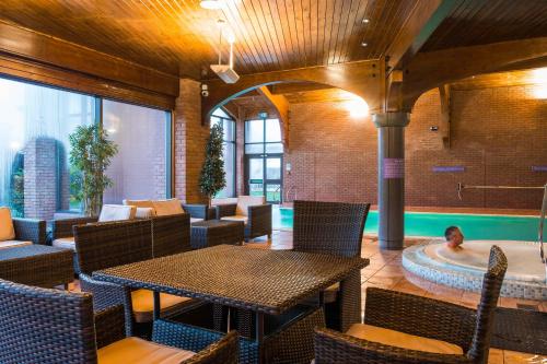a restaurant with a table and a swimming pool at Abbey Hotel Golf & Spa in Redditch