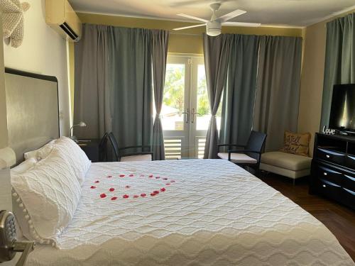 ein Schlafzimmer mit einem weißen Bett mit roten Rosenblättern drauf in der Unterkunft Bella Noni B&B in Aguadilla