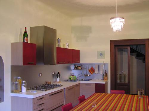 eine Küche mit roten Schränken und einem Tisch mit einer Flasche Wein in der Unterkunft Bed & Breakfast Villa Palma in Lovere