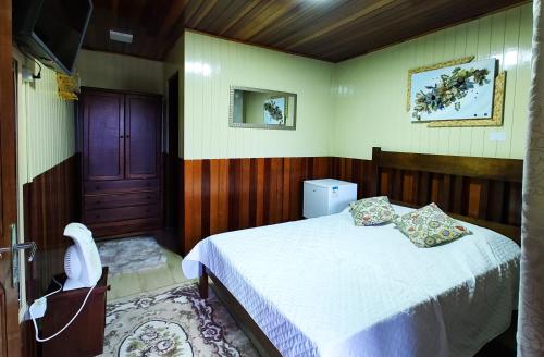 a bedroom with a bed and a chair in it at Pousada Casa dos Sonhos in Campos do Jordão