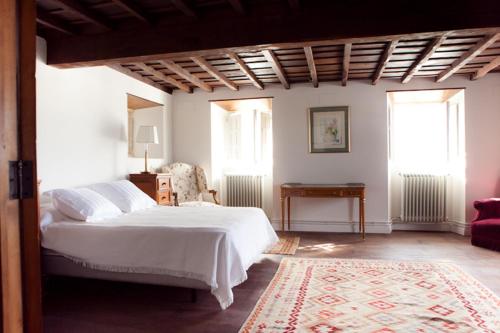 1 dormitorio con 1 cama blanca y 2 ventanas en Casona Puerto de Vega, en Puerto de Vega