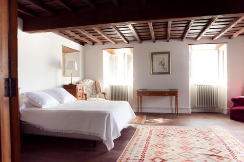 a bedroom with a white bed and two windows at Casona Puerto de Vega in Puerto de Vega