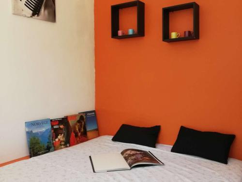 a bedroom with an orange wall and a bed with a book at Appartement La Rochelle, 2 pièces, 4 personnes - FR-1-246-555 in La Rochelle