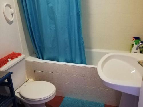 a bathroom with a toilet and a sink and a blue shower curtain at Appartement La Rochelle, 2 pièces, 4 personnes - FR-1-246-555 in La Rochelle