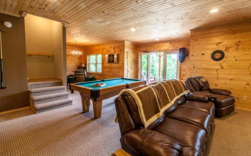 a living room with a pool table and leather couches at High Road Cabin in Banner Elk
