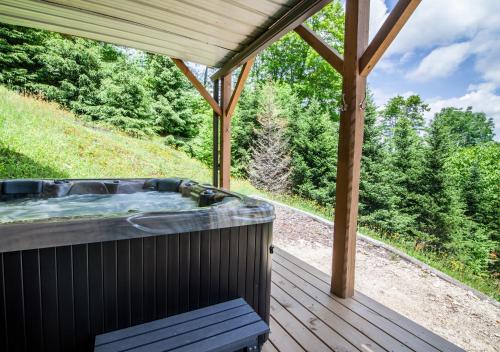 a hot tub on a wooden deck with a view at High Road Cabin in Banner Elk